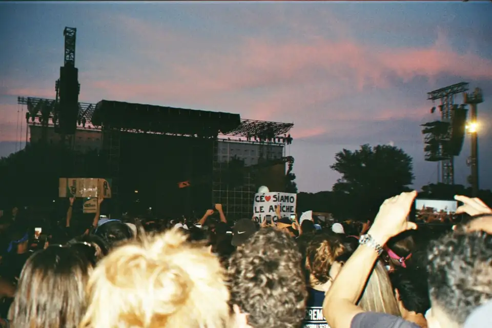 A crowd at an outdoor concert at sunset.